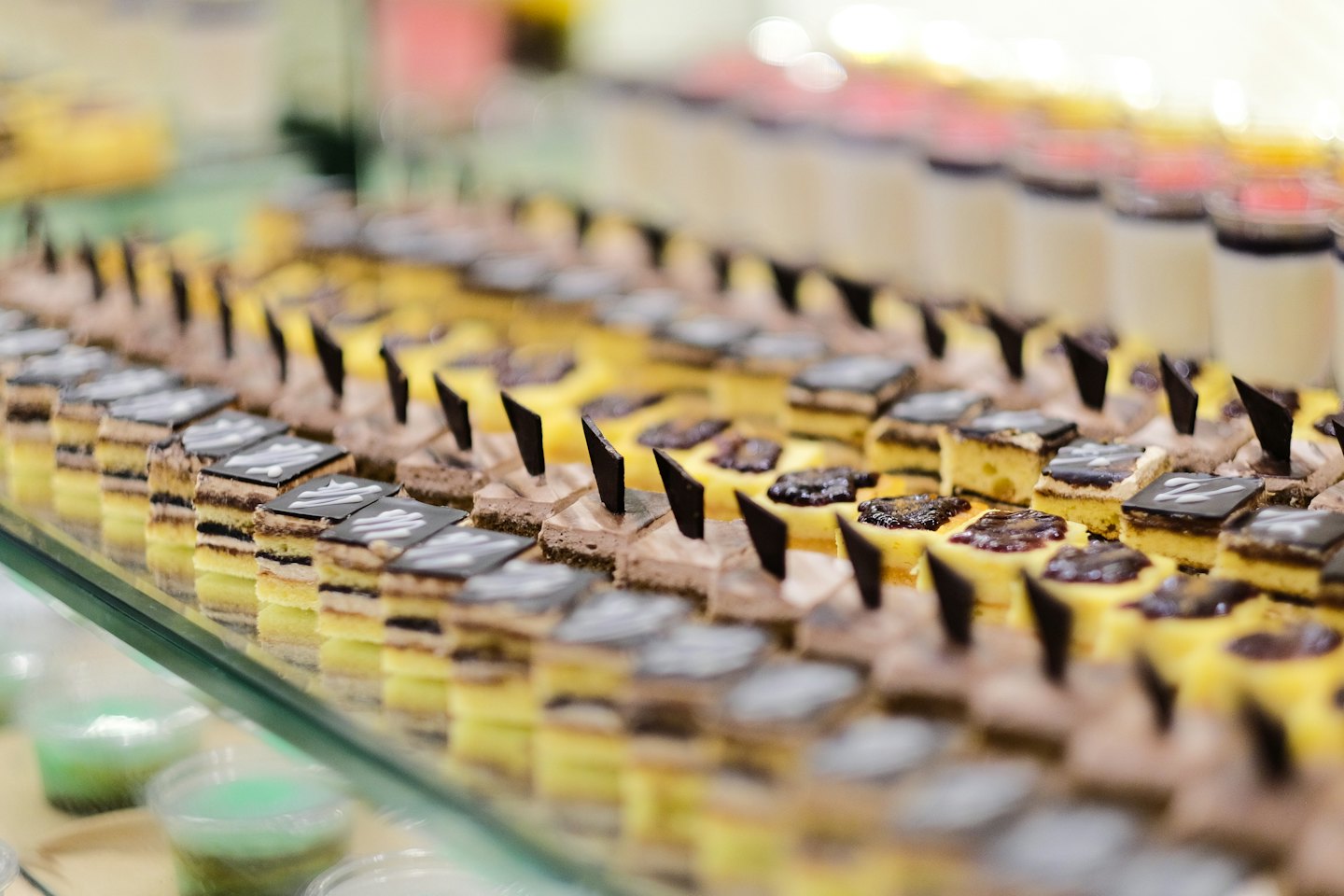 Mini desserts arranged in neat rows on a glass shelf.