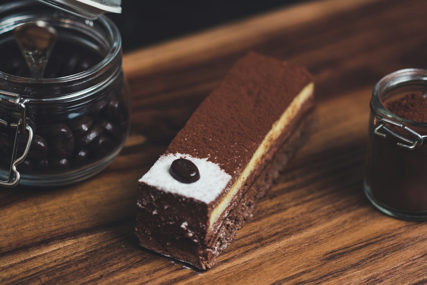 A square chocolate dessert topped with a single coffee bean.