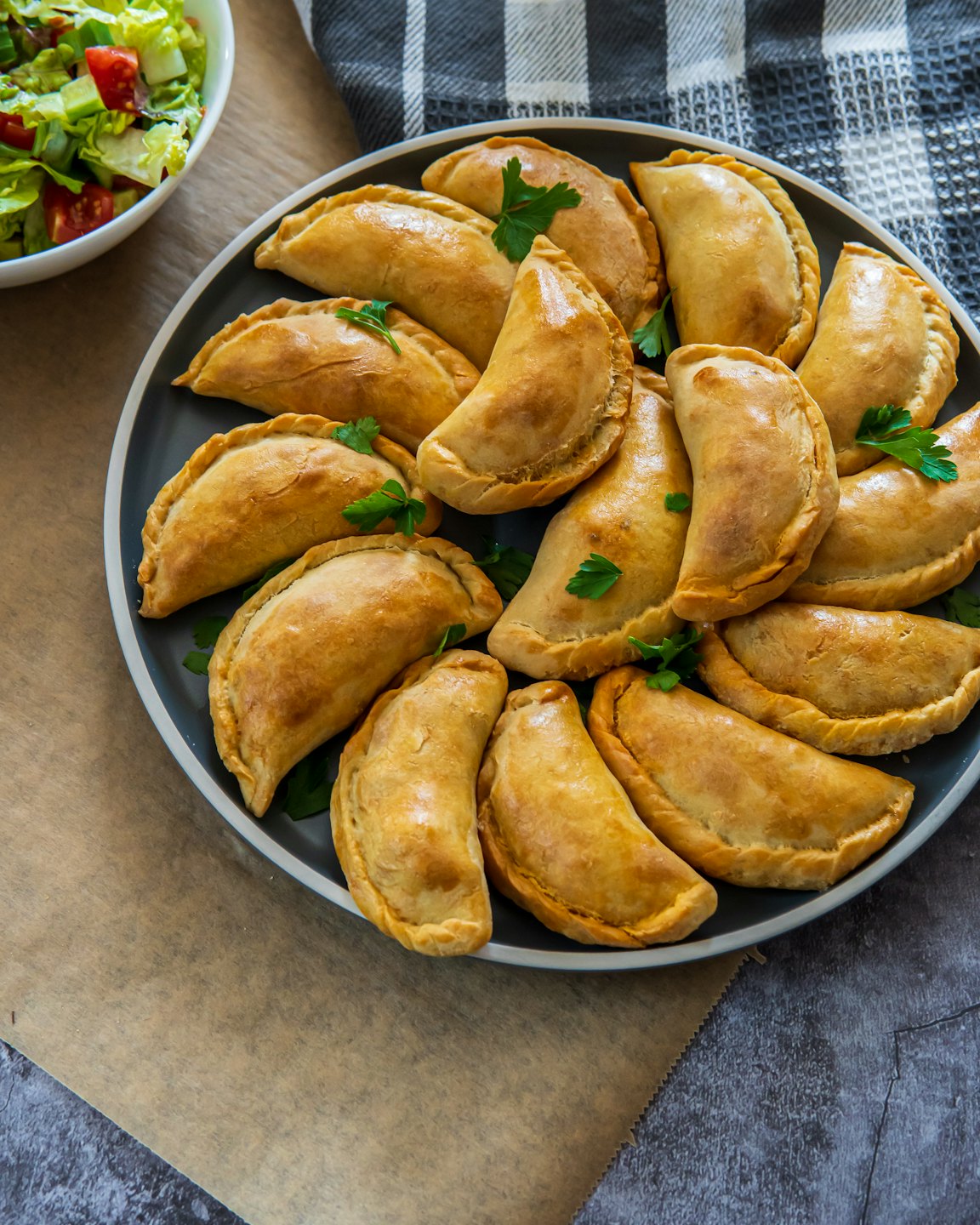 Golden-brown empanadas arranged on a dark grey platter.